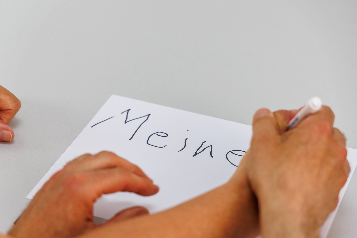 Patientin schreibt „Meine Ziele“ auf ein Blatt, der Therapeut führt ihre Hand