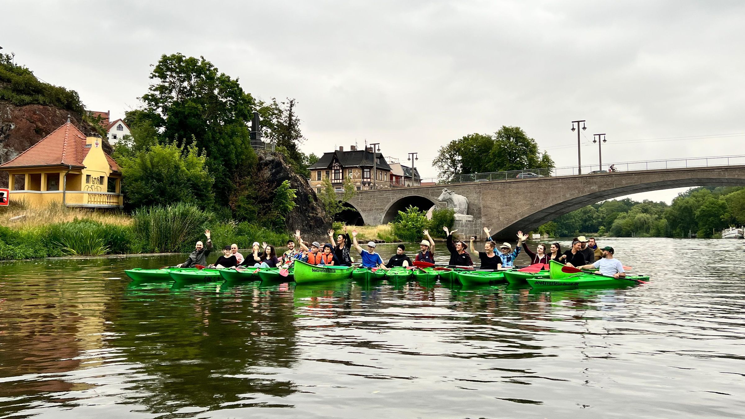 Team des Therapiezentrums in grünen Kajaks auf der Saale vor der Kröllwitzer Brücke
