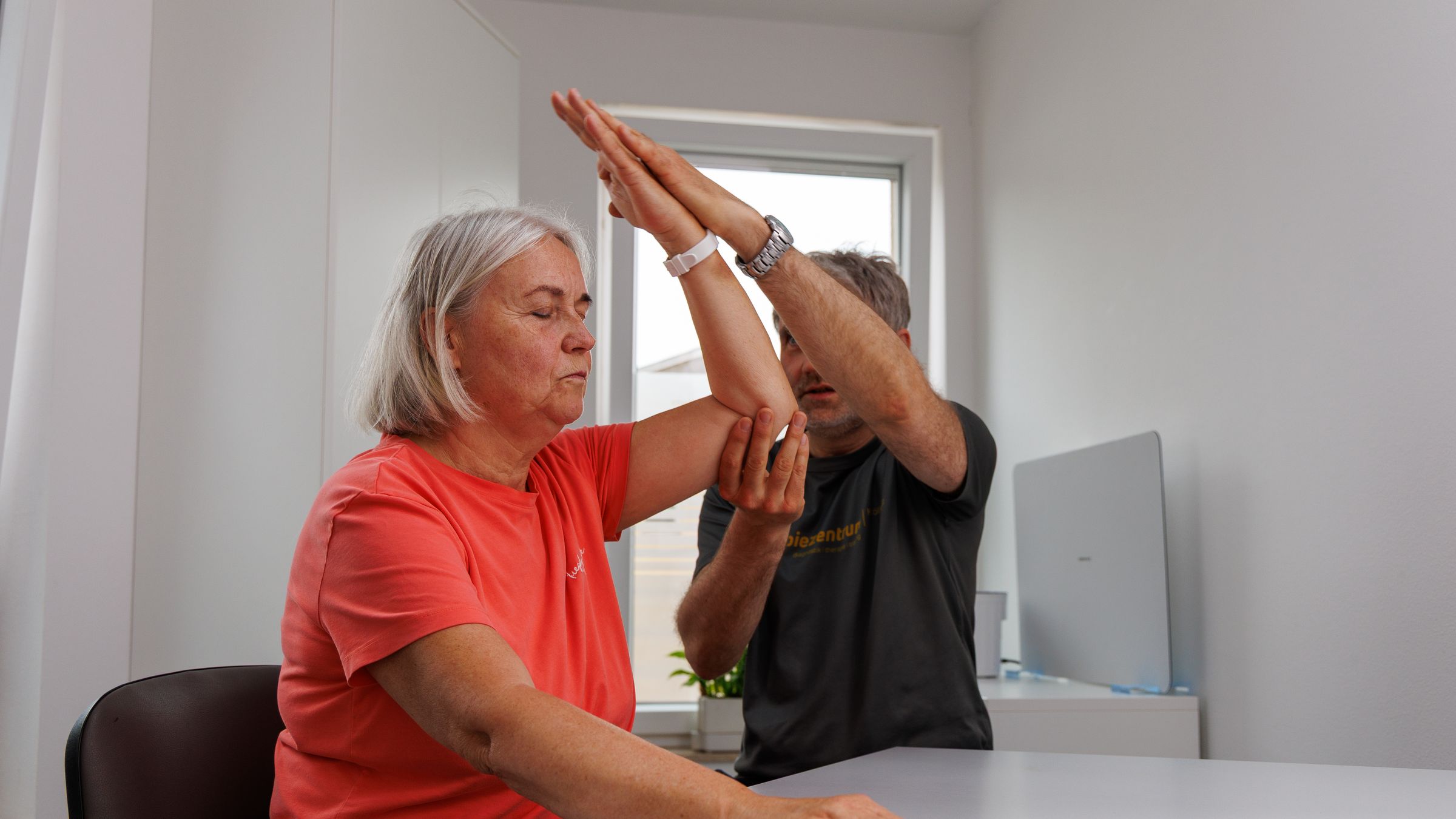 Therapeut führt beide Arme einer Patientin über den Kopf