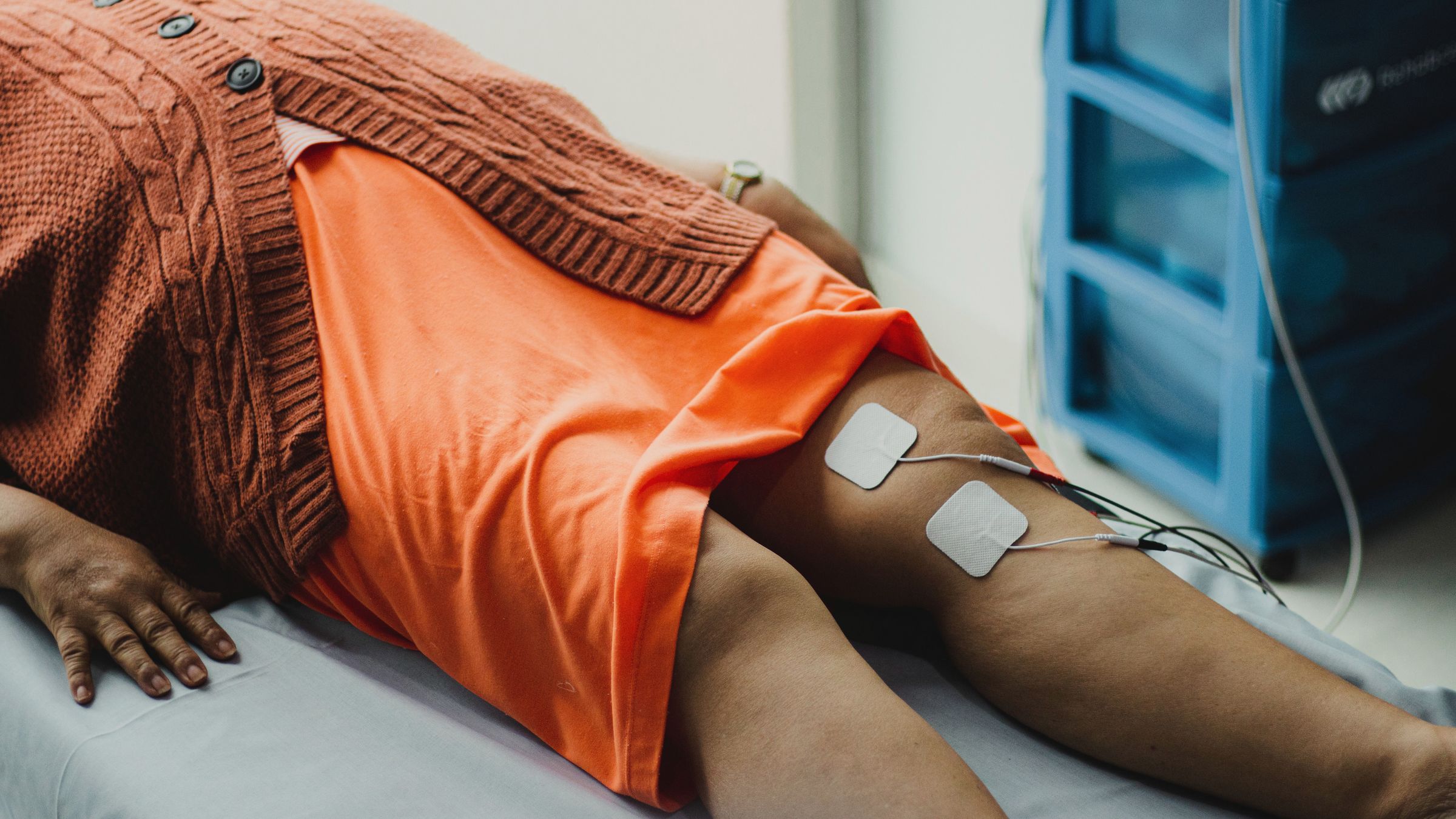 Elektroden der Elektrotherapie am Oberschenkel einer liegenden Patientin