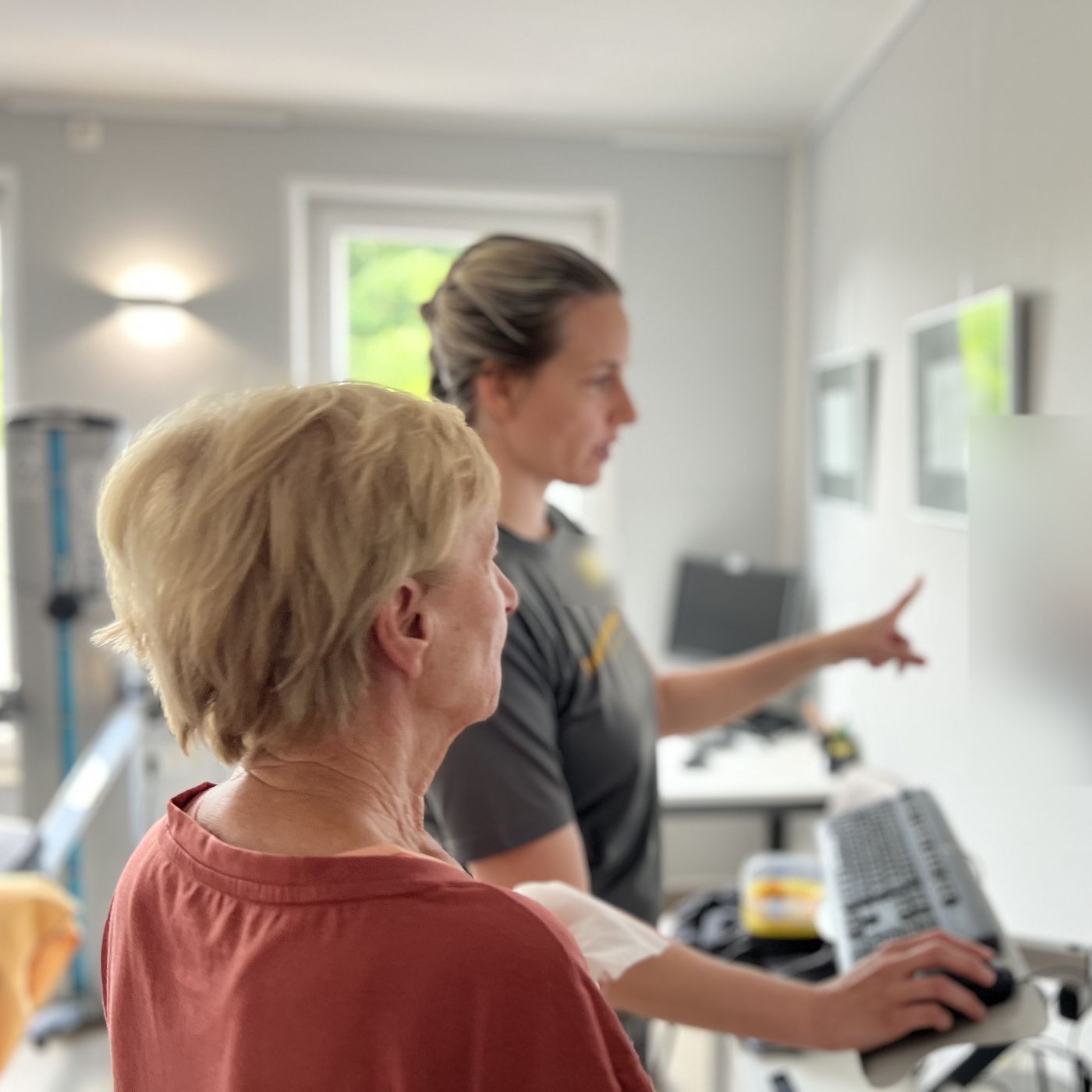 Therapeutin zeigt einer Patientin am Bildschirm den Trainingsplan