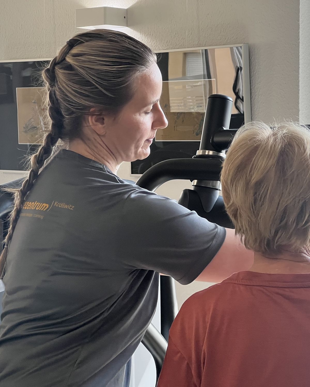 Therapeutin stellt einer Patientin ein Trainingsgerät ein